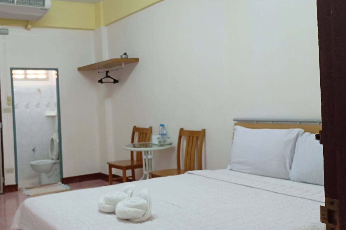 Une chambre d’hôtel comprenant un lit, un bureau, une chaise, une petite table, une télévision et une salle de bain avec des toilettes et un lavabo.
