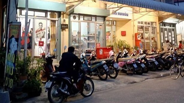 Een meerlaags gebouw met een winkel op de begane grond en meerdere motorfietsen ervoor geparkeerd.