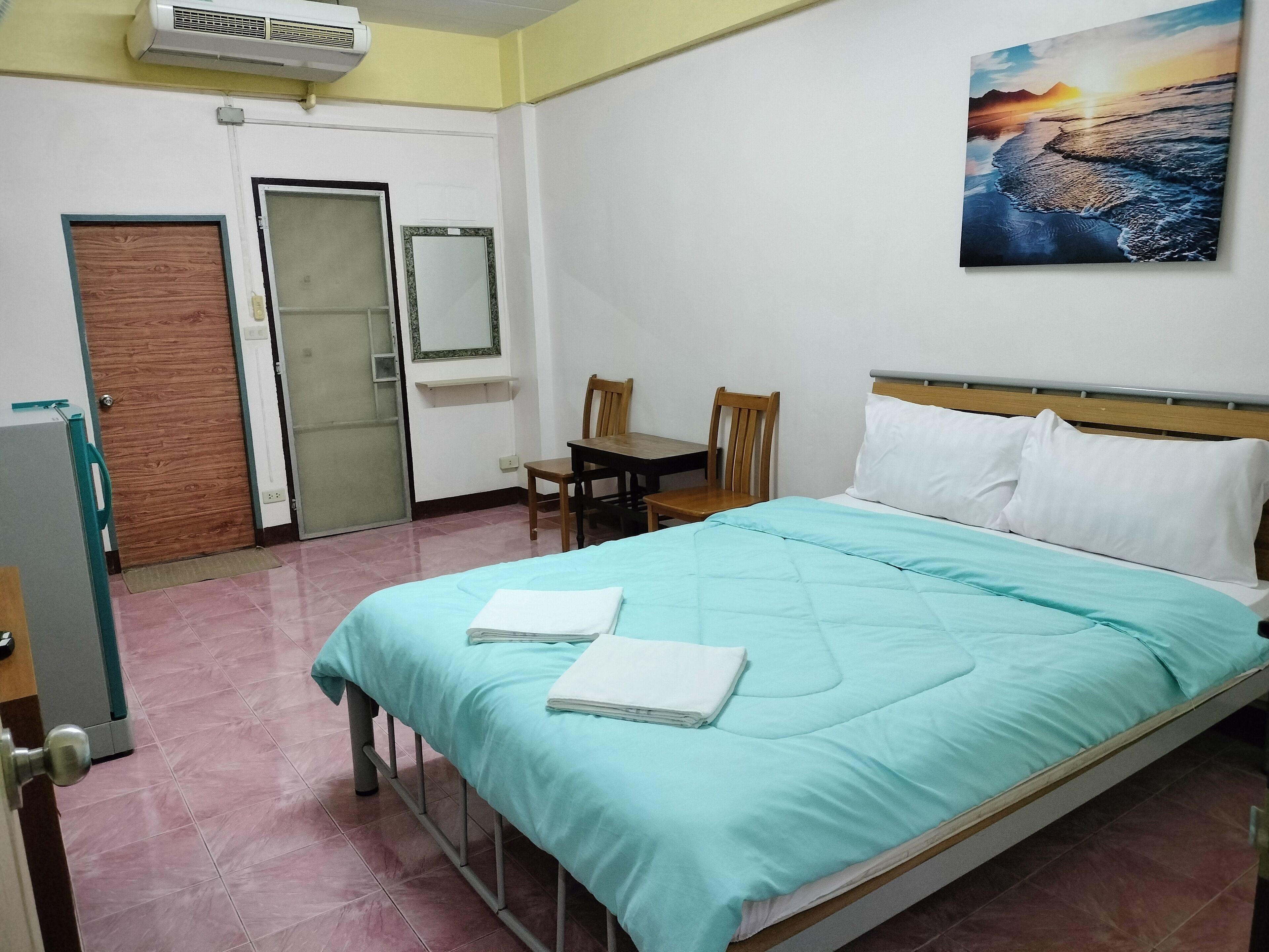A neatly arranged bedroom with a bed, a chair, a desk, and a painting on the wall.