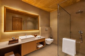 A modern bathroom with a wooden vanity, a large mirror, a glass shower enclosure, and a towel rack.