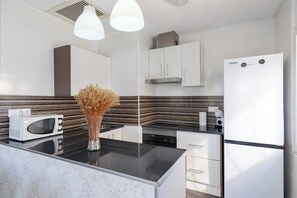 Una cocina moderna con microondas, un jarrón con flores secas y un refrigerador.
