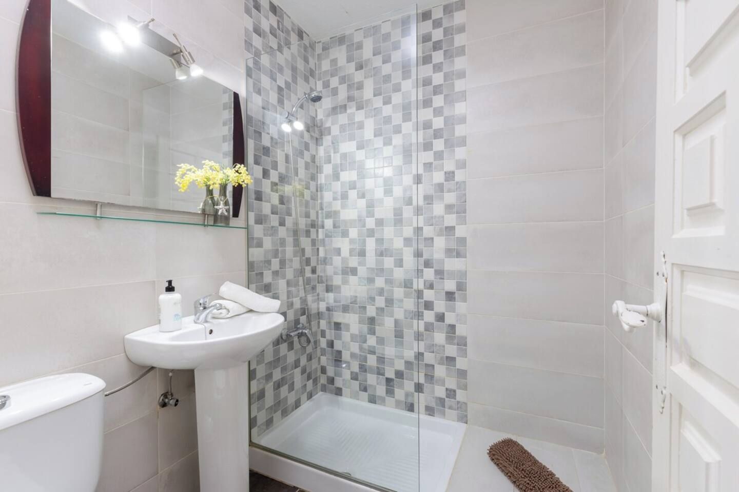 Une salle de bain avec une douche à parois de verre, un lavabo blanc et des toilettes.