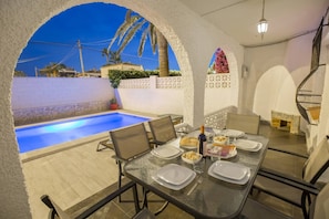 An outdoor dining area with a pool, tables, chairs, and a staircase.