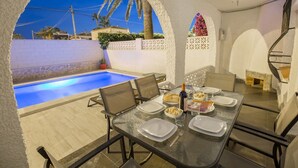A dining area with a pool view, outdoor seating, and a spiral staircase. - Fidalsa Relax Pool your Refuge (Torrevieja)