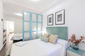 A hotel room with a bed, bedside table, and a view of the hallway.