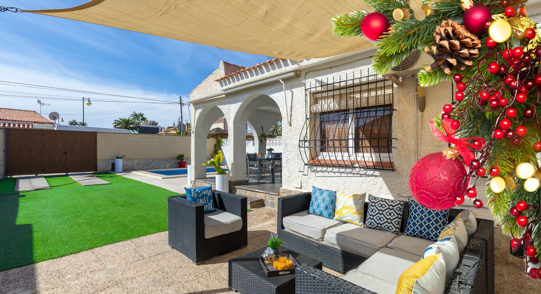 An outdoor patio with wicker furniture, a pool, and a covered area with arches.