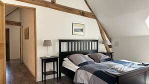 A bedroom with a sloped ceiling, a bed with a headboard, two bedside tables with lamps, and a framed picture on the wall. - Cottage in an old farmhouse (Frémainville)