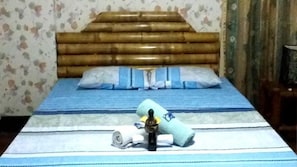 A bed with a wooden headboard, blue bedding, and a rolled towel.