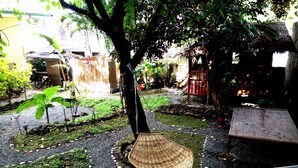 Un jardín con un banco tejido, un árbol y una planta pequeña.