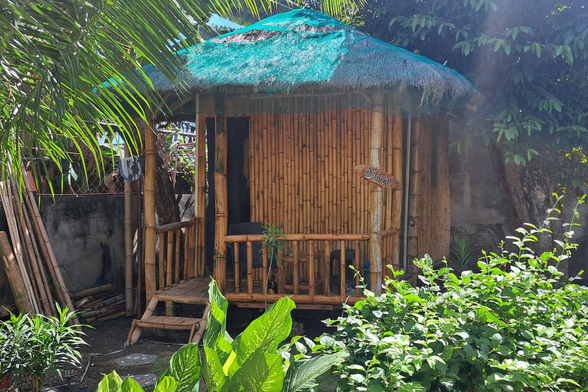 Une hutte en bambou avec un toit de chaume, un banc en bois et une pancarte indiquant « Biliran ».