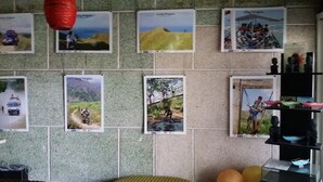 Pared con varios carteles de ciclismo, un objeto rojo colgante y una estantería con cuencos.