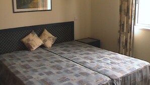 Un letto matrimoniale con copriletto decorato, due cuscini, una testiera, un comodino e una finestra con tende.