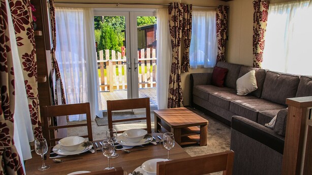 Un coin repas avec une table dressée pour quatre personnes, un canapé et une petite table en bois.