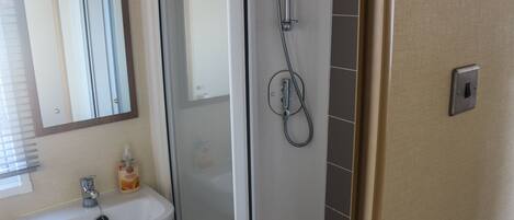 A bathroom with a shower, a sink, and a mirror.