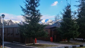 Un bâtiment rustique en bois, avec une vue sur les montagnes en arrière-plan, un lampadaire et un chemin de gravier.