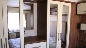 Une chambre à coucher comprenant un lit, une armoire avec des portes miroir et une table de chevet.