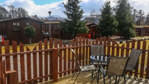 Une terrasse en bois avec une table et des chaises, entourée d’une clôture en bois.