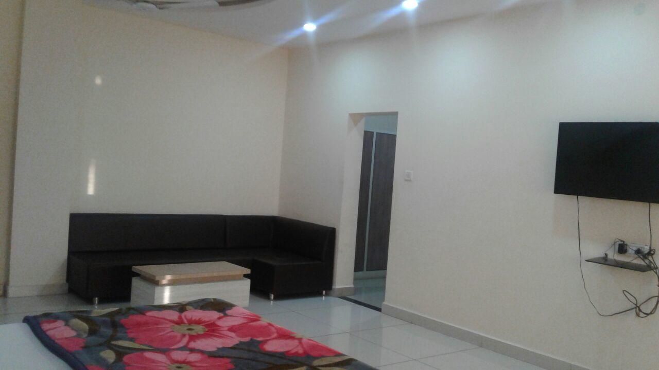 Una sala de estar moderna con un sofá negro, una mesa de centro y un televisor de pantalla plana montado en la pared.