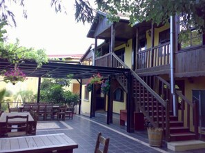 A courtyard with wooden tables and chairs, a covered seating area, and a staircase leading to a second floor. - Santa Roza Butik Otel (Beykoz)