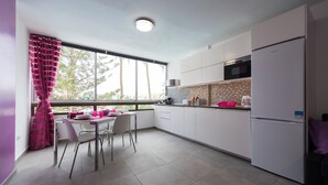 A modern kitchen with white cabinets, a refrigerator, and a dining area with a table and chairs. - Charming apartment with swimming pool 5 min from the sea  (San Bartolomé de Tirajana)