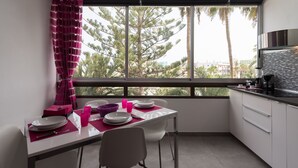 A modern kitchen with a dining area, large windows, and a view of trees. - Charming apartment with swimming pool 5 min from the sea  (San Bartolomé de Tirajana)