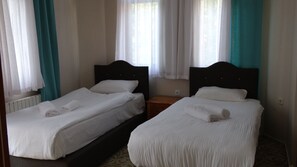 Two single beds with white linens, a wooden nightstand, and a window with sheer curtains. - Bolu Yildiz Hotel (Bolu)