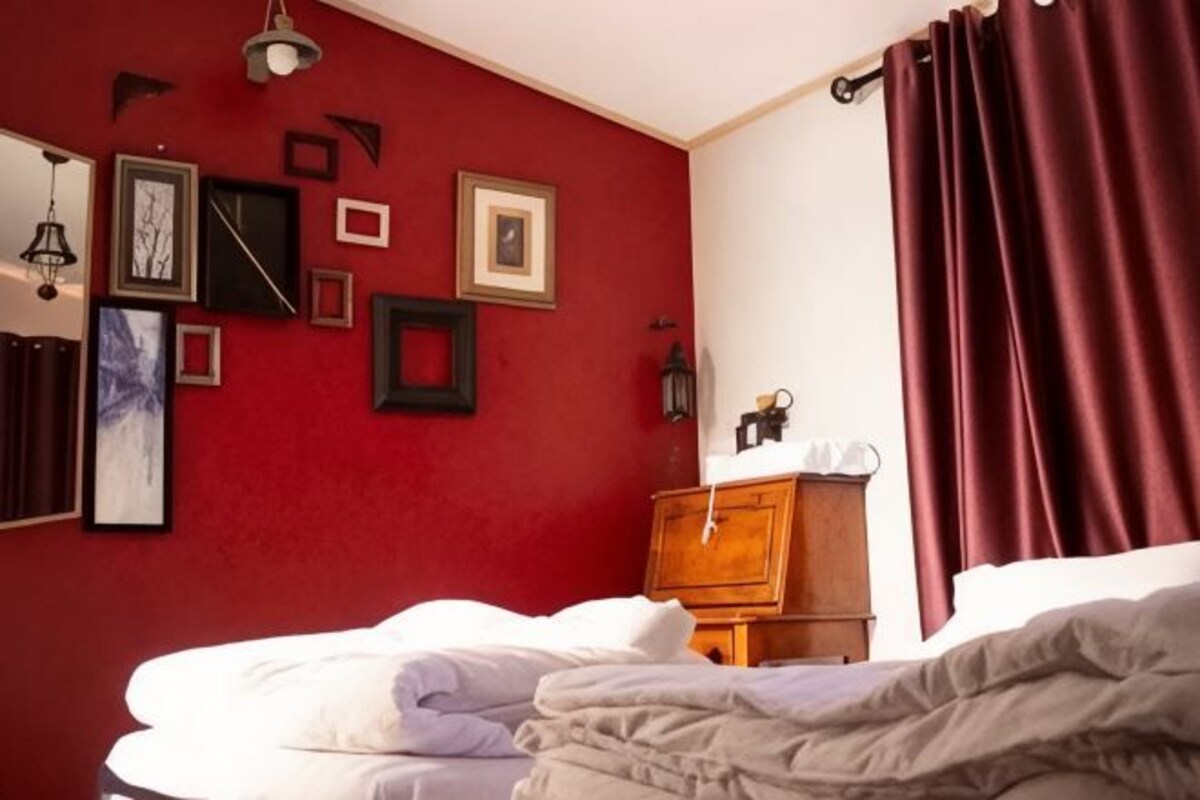 A bedroom with a bed, a dresser, and a wall with framed pictures.