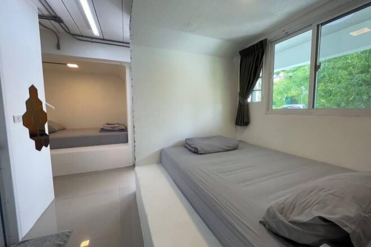 A modern room with a bed, a small seating area, and a window with a view of greenery.