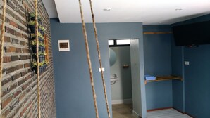 Habitació amb paret de maó, paret blava, prestatge de fusta, rentapelats i mirall.