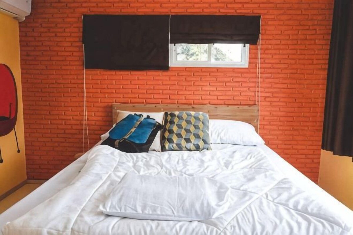 A bed with white bedding, a wooden headboard, and patterned pillows.