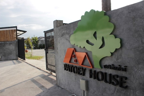 A concrete wall with a logo and text for "Patoey House" and a tree silhouette.