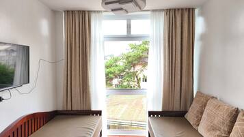 A room with two beds, a TV, and a view of a residential area.