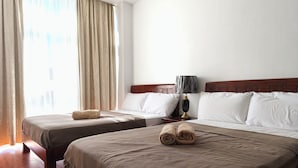 Ein Hotelzimmer mit zwei Betten, einem hölzernen Kopfteil, einem Nachttisch mit Lampe und einem Fenster mit Vorhängen.