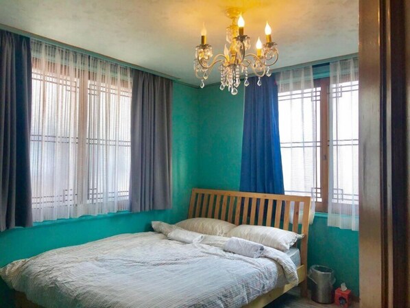 Un dormitorio con una cama de madera, un candelabro y cortinas en las ventanas.