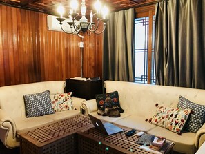 Una sala acogedora con un sofá color beige, cojines estampados, una mesa de centro de madera y una computadora portátil.