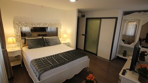 Une chambre à coucher bien rangée, avec un grand lit, des lampes de chevet, une commode et un miroir.