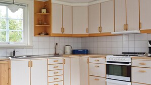 Una cocina con armarios blancos, estufa y pileta.