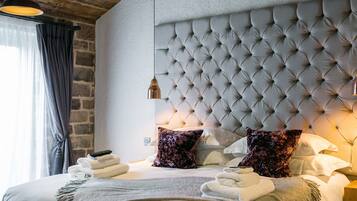 Quarto com cabeceira estofada, cama com toalhas dobradas e luminária pendente.