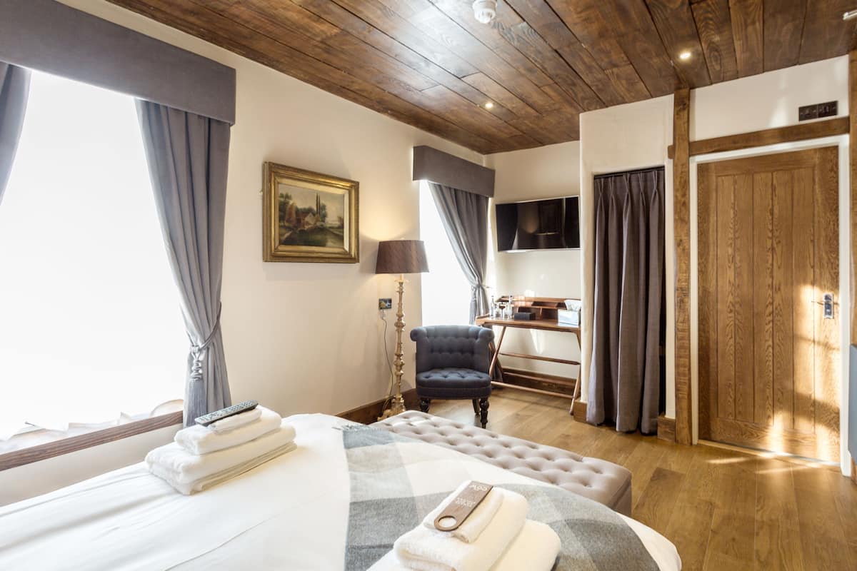 A hotel room with a large bed, a chair, a desk, and a television.