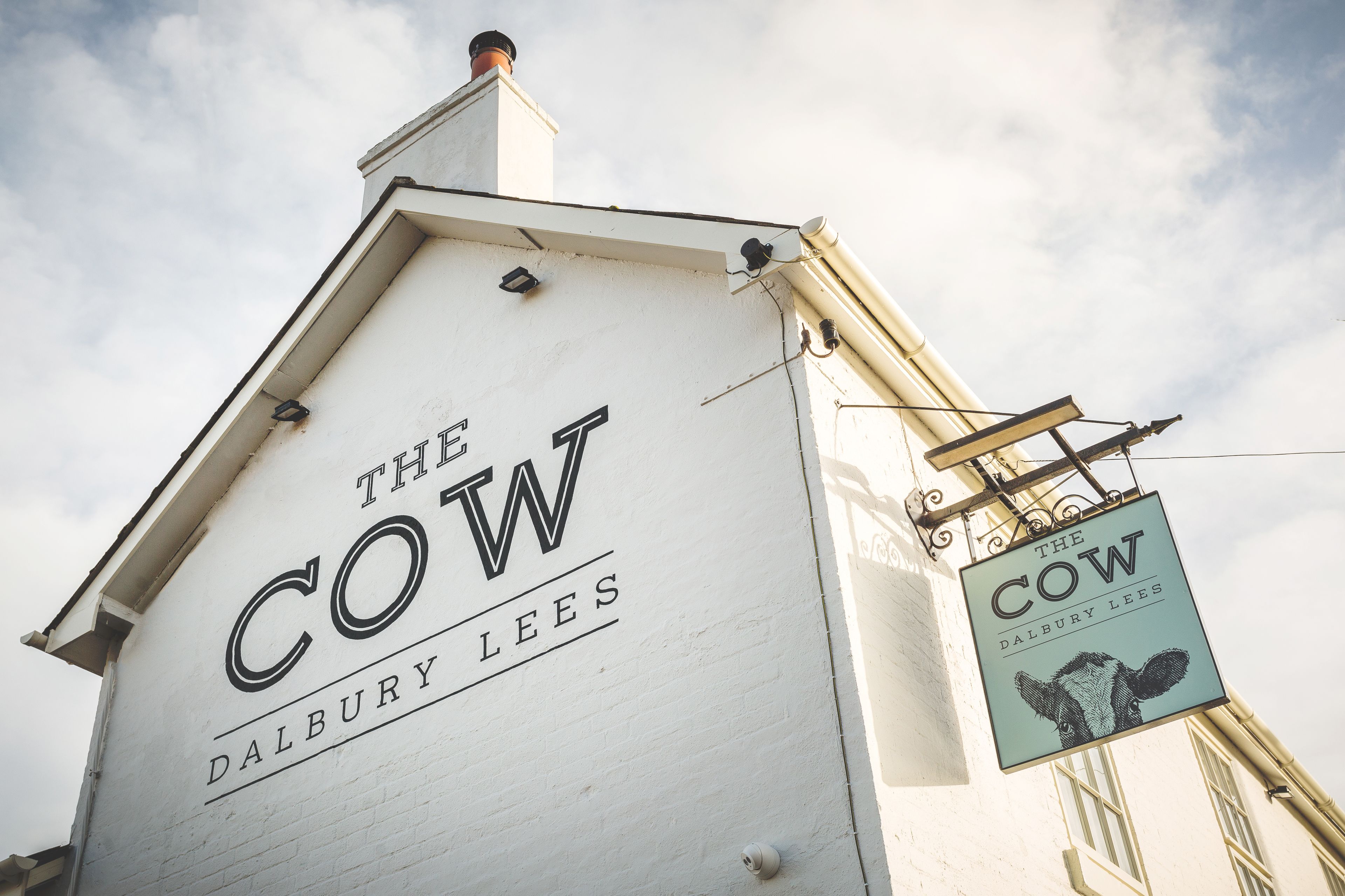 Een gebouw met een bord waarop 'The Cow Dalbury Lees' staat.