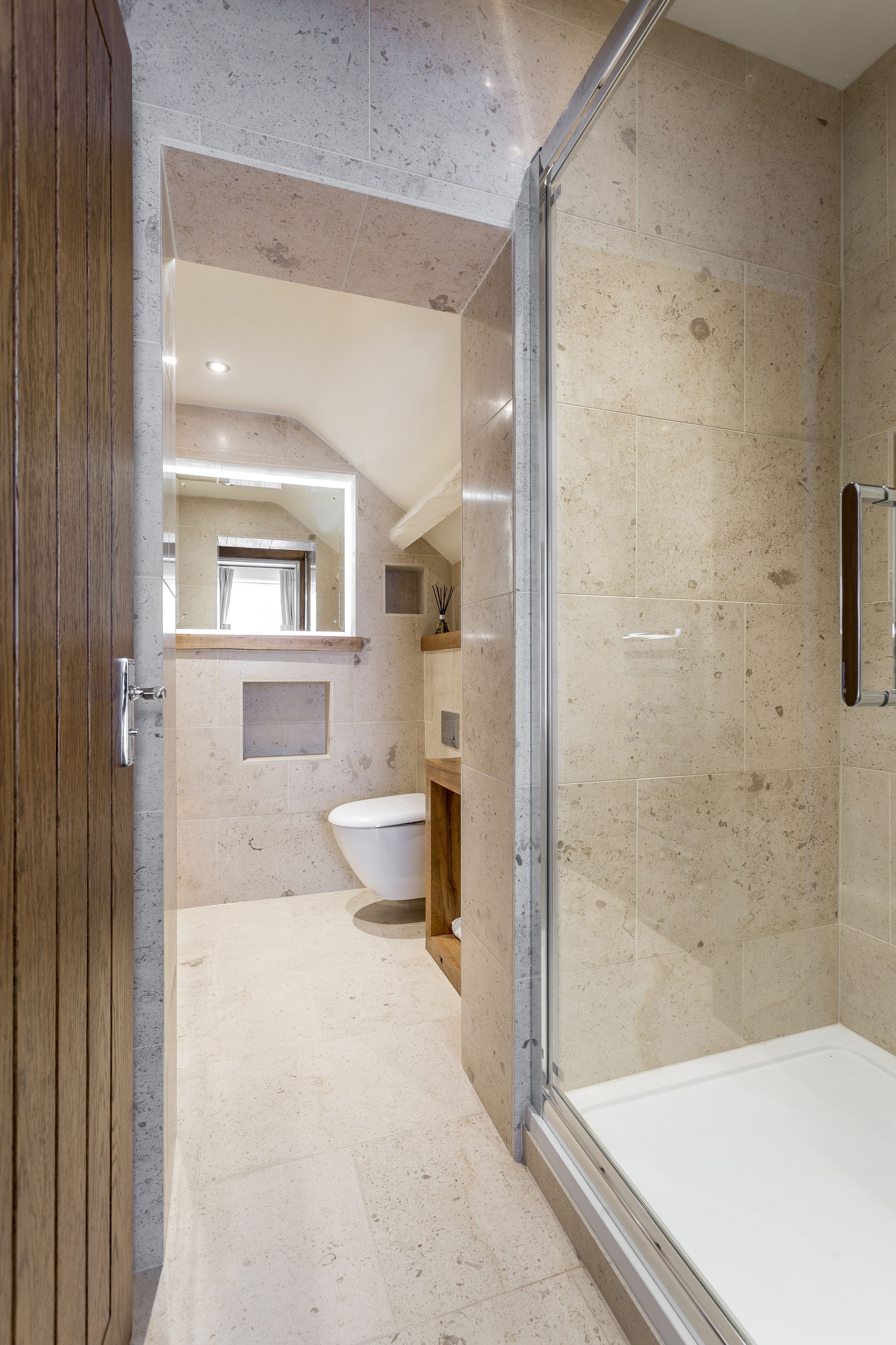 Un baño moderno con ducha de vidrio, puerta de madera y un espejo grande.