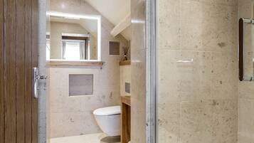 Un baño moderno con ducha de vidrio, puerta de madera y un espejo grande.