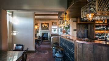 A bar area with wooden bar counters, a fireplace, and a dining area with chairs and a table.
