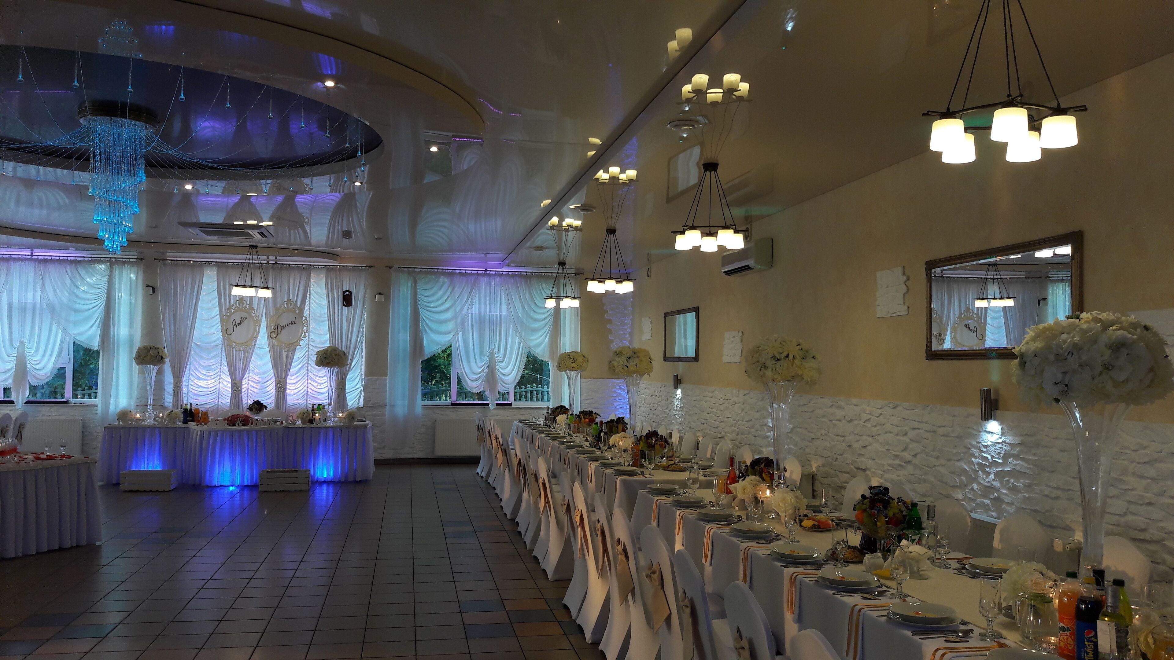 Un salón de banquetes con mesas largas, manteles blancos y candelabros.