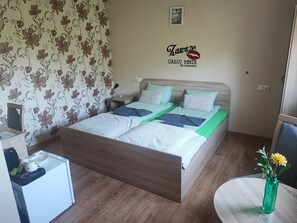 A bedroom with a bed, bedside table, and a small table with a vase of flowers.