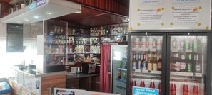 A bar area with shelves stocked with various bottles and a refrigerator with drinks.
