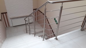 Un escalier avec des rampes en métal et un mur blanc orné d’un motif texturé.