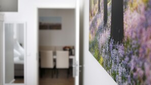 A room with a dining area and a large painting of purple flowers. - SC_3 box spring beds +70 sqm + 3 rooms + balcony + elevator (Berlin)