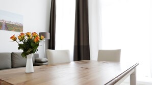 A dining table with a vase of flowers, a sofa, and a lamp in a modern living room. - SC_3 box spring beds +70 sqm + 3 rooms + balcony + elevator (Berlin)