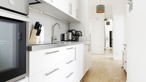 A modern kitchen with white cabinets, stainless steel appliances, and a wooden floor. - SC_3 box spring beds +70 sqm + 3 rooms + balcony + elevator (Berlin)